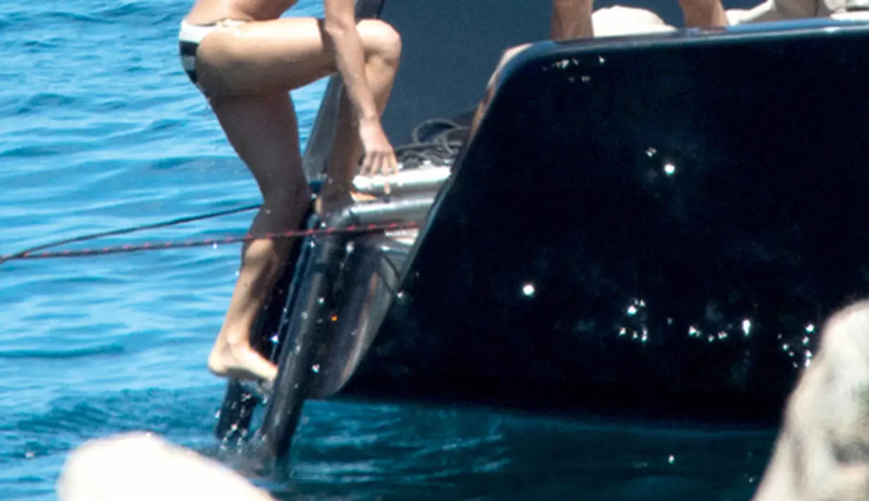 Zac Efron membantu Michelle Rodriguez  untuk naik ke kapal usai menyeburkan diri ke pantai, Pulau Sardinia, Italia, Selasa (8/7/2014) (mzn.com)