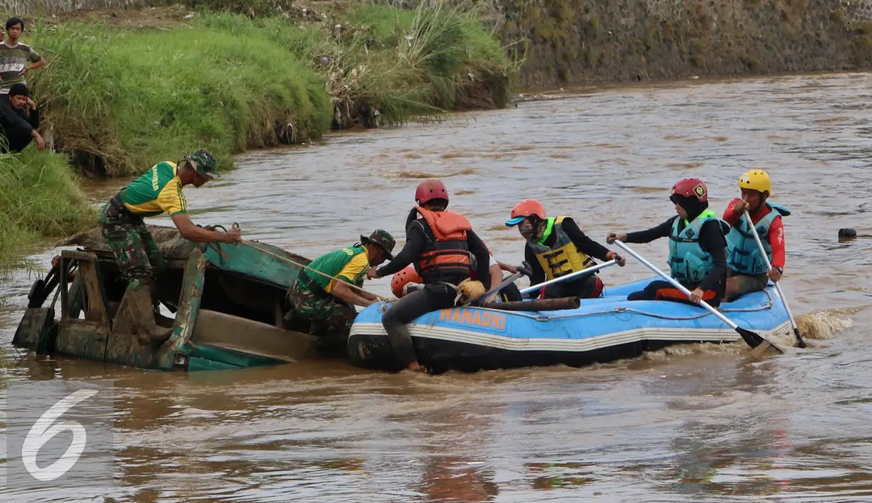 Prajurit TNI dan sukarelawan menyisir bangkai mobil yang diduga terdapat jenazah korban musibah banjir bandang di Cimacan, Garut (23/9). Data terakhir, korban jiwa mencapai 26 orang dan warga yang dilaporkan hilang 23 orang. (Liputan6.com/Johan Tallo)