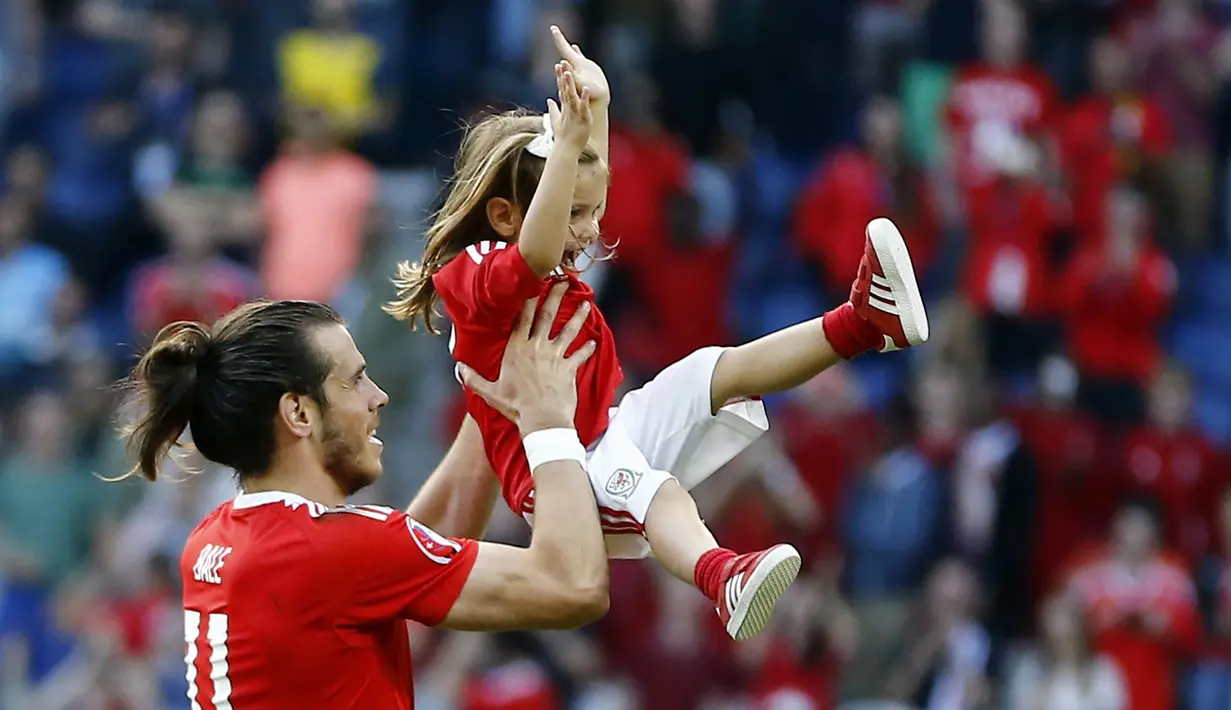 Gareth Bale merayakan kemenangan bersama putrinya usai laga melawan Irlandia Utara pada Piala Eropa 2016 di Parc des Princes, Paris, (25/6/2016). Wales Menang 1-0. (EPA/Georgi Licovski)