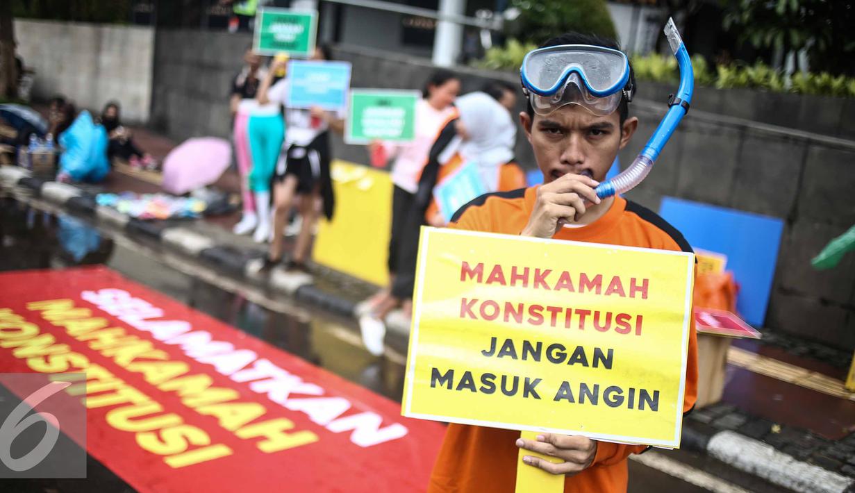 Seorang pria yang tergabung dalam ICW menunjukan poster saat menggelar aksinya di Car Free Day dikawasan Bunderan HI, Jakarta, Minggu (12/2). Menurut pihak ICW lembaga peradilan saat ini butuh diselamatkan. (Liputan6.com/Faizal Fanani)