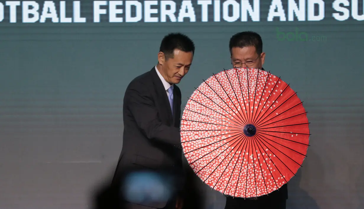 Direktur PT. Suzuki Indomobil Motor, Seiji Itayama memberikan hadiah payung kepada Deputi Presiden AFF, Maj Gen Khiev Sameth di Hotel Mulia, Jakarta, Rabu (2/5/2018). Indonesia berada satu grup dengan Thailand. (Bola.com/Nick Hanoatubun)