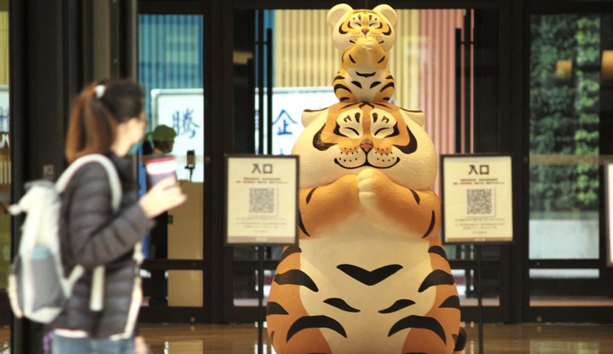 Warga berjalan melewati patung macan di depan pusat perbelanjaan jelang Tahun Baru Imlek di Taipei, Taiwan, 27 Januari 2022. Tahun Baru Imlek 2022 yang jatuh pada 1 Februari mendatang akan jadi tahun shio macan. (Sam Yeh/AFP)
