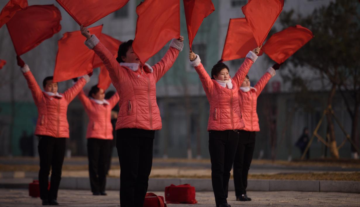Kelompok Serikat Wanita Sosialis mengibarkan bendera saat melakukan propaganda di depan Hotel Ryugyong, Pyongyang, Korea Utara, Sabtu (9/3). Semua wanita Korea Utara yang tidak bekerja adalah anggota Serikat Wanita Sosialis. (Ed Jones/AFP)