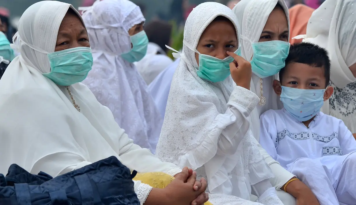 Umat muslim mengenakan masker saat mendengarkan ceramah usai melaksanakan salat Idul Adha di halaman Masjid Raya Annur, Kota Pekanbaru, Riau, Minggu (11/8/2019). Kabut asap imbas kebakaran hutan dan lahan (karhutla) menyelimuti pelaksanaan salat Idul Adha 2019 di Pekanbaru. (Wahyudi/AFP)