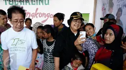 Menteri LHK, Siti Nurbaya (baju hitam) berfoto bersama pedagang jamu sebelum  pelepasan mudik gratis Sido Muncul di kawasan TMII, Jakarta, Jumat (7/1). Mudik gratis yang ke-27 ini memberangkatkan sebanyak 16 ribu pedagang jamu. (Liputan6.com/Fery Pradolo)