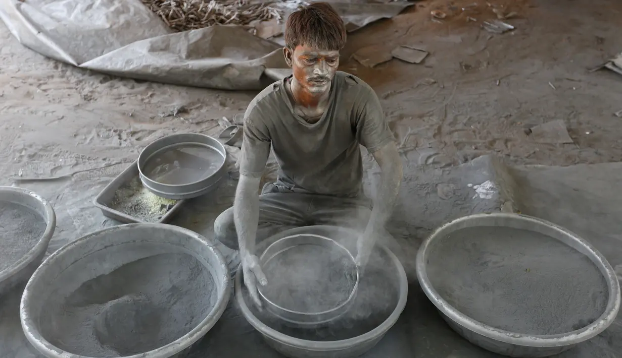 Seorang pekerja menyaring bubuk mesiu untuk membuat petasan, di sebuah pabrik pinggiran  Ahmadabad, Senin (22/10). Permintaan petasan di India semakin meningkat jelang perayaan Festival "Cahaya" Diwali bagi umat Hindu. (AP/Ajit Solanki)