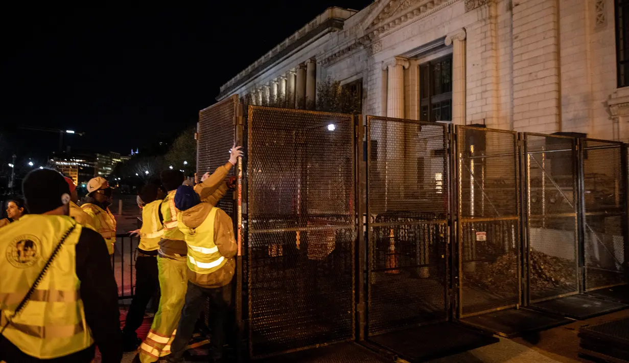 Pekerja memasang pagar besi di pintu masuk Gedung Putih mengantisipasi kerusuhan menjelang Pilpres Amerika Serikat di Washington DC, Senin (2/11/2020). Sebagai persiapan kemungkinan ada aksi terorisme atau protes massa, Gedung Putih membangun pagar baru. (Chris McGrath/Getty Images/AFP)
