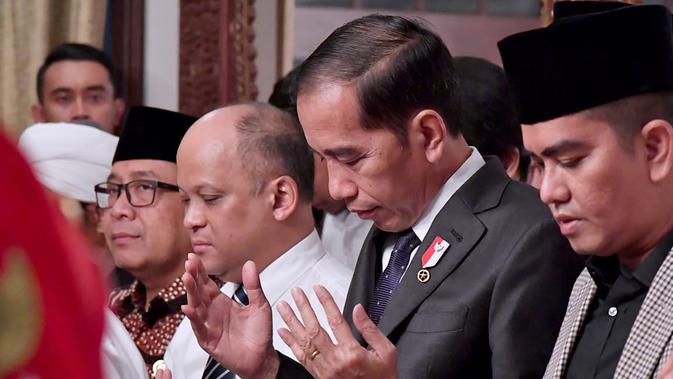 Presiden Joko Widodo atau Jokowi memanjatkan doa untuk Presiden ke-3 RI BJ Habibie saat melayat ke rumah duka di Patra Kuningan, Jakarta, Kamis (12/9/2019). Jokowi akan memimpin upacara pemakaman Habibie di TMP Kalibata. (Handout/Indonesian Presidential Palace/AFP)