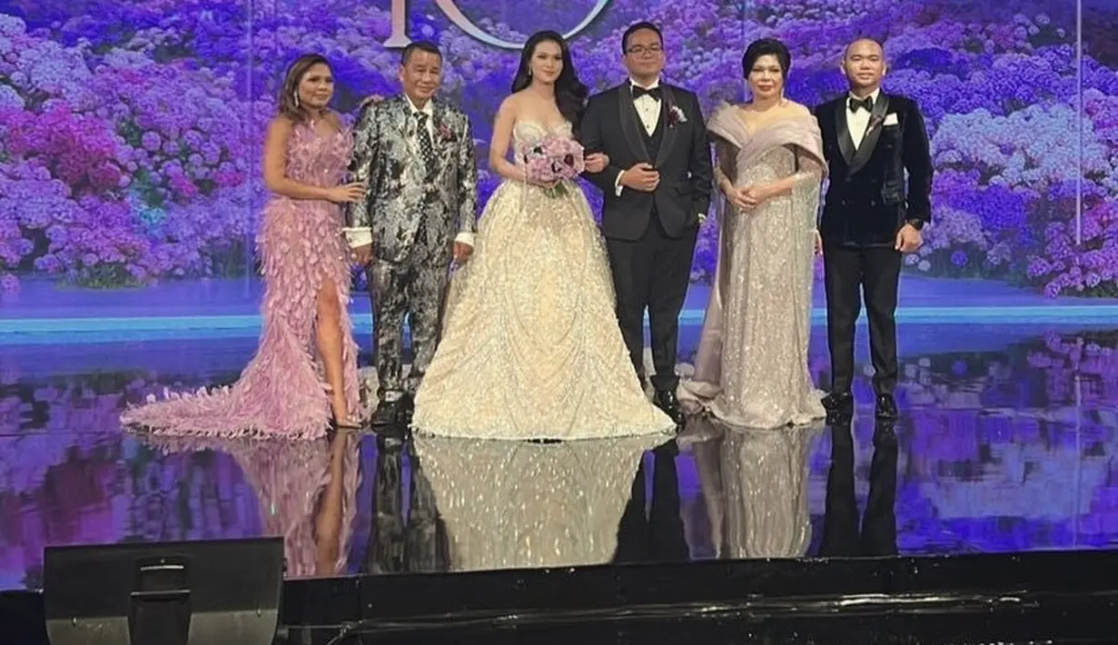 Saat resepsi pernikahan sang adik, Felicia mengenakan gaun slit off shoulder warna ungu dengan detail bulu-bulu yang menyapu lantai. [@fcgweddings]