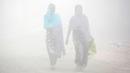Warga berjalan melalui kabut tebal akibat polusi di Delhi, India (1/12). Sekitar 26 penerbangan ditunda atau dialihkan di Delhi sementara tiga dibatalkan, menurut situs IGI. (REUTERS/Cathal McNaughton)