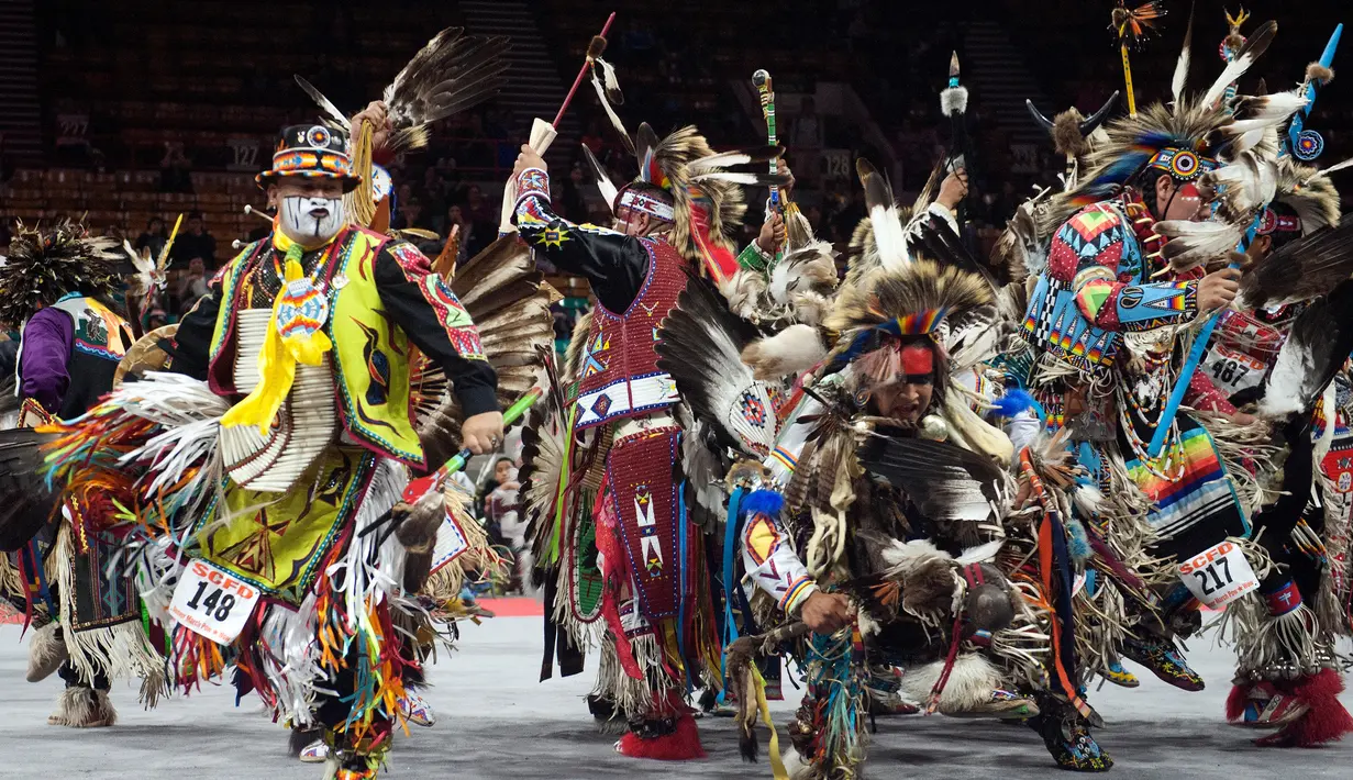 Penampilan para penari saat mengikuti Grand Entry of the Denver March Powwow di Denver, Colorado (24/3). Para penari mengenakan pakaian tradisional serta hiasan kepala, sepatu dan syal dari sukunya masing-masing yang unik. (AFP/Jason Connolly)