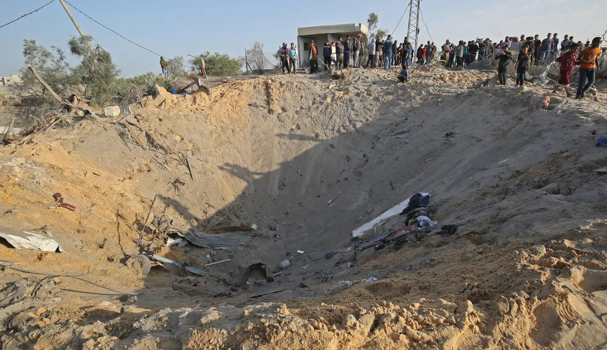Warga Palestina melihat kawah besar bekas serangan udara Israel di Deir al-Balah di Jalur Gaza selatan, Kamis (14/11/2019). Kementerian Kesehatan Gaza mengatakan, 32 warga Palestina, termasuk anak-anak, telah tewas oleh serangan Israel sejak Selasa (12/11) waktu setempat. (SAID KHATIB/AFP)