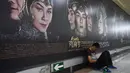 Seorang pria tertidur di depan poster film Asura di stasiun kereta bawah tanah di Beijing, Selasa (17/7). Namun film tersebut hanya menghasilkan kurang dari 50 juta yuan  atau sekitar Rp107,5 miliar pada pembukaannya. (AFP/GREG BAKER)