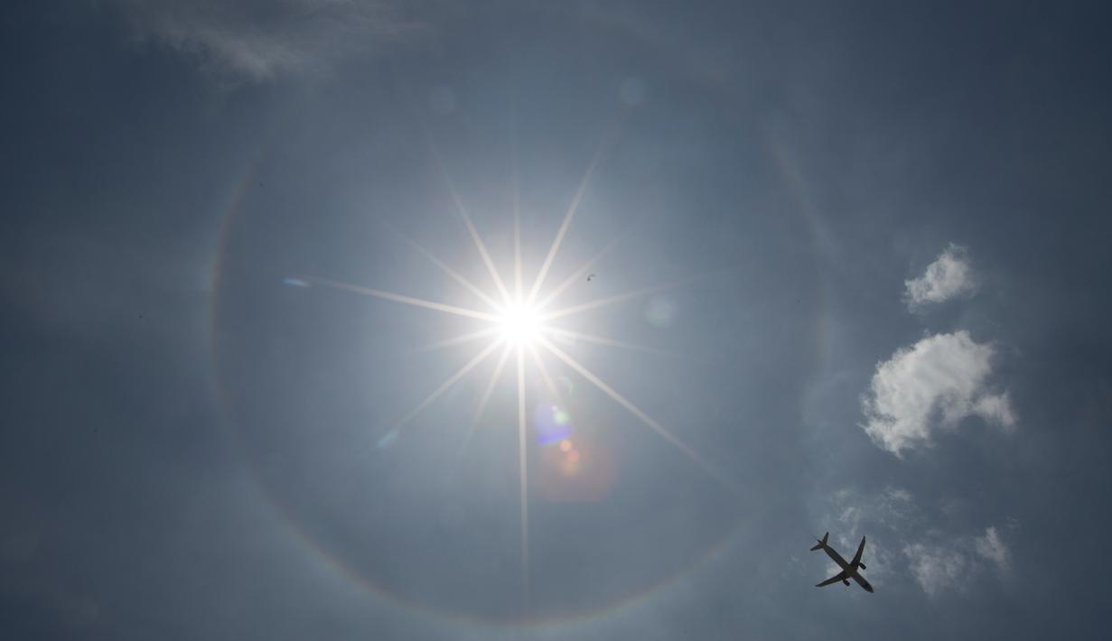 Pesawat komersil melintas dilatari fenomena halo matahari di Meksiko, Sabtu (7/7). Fenomena halo matahari terjadi karena pembiasan kristal es yang berada di sekitar matahari sehingga membentuk cincin pelangi yang mengelilingi matahari (AP/Moises Castillo)