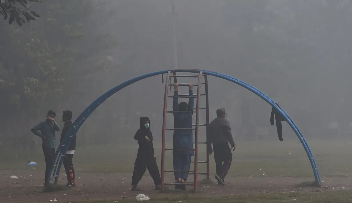 Anak-anak bermain di taman di tengah kondisi asap tebal di Lahore (21/11/2019). Lahore pada hari Kamis (21/11) menduduki peringkat global untuk kota dengan kualitas udara terburuk dan berbahaya. (AFP Photo/Arif Ali)