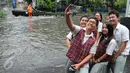 Sejumlah pelajar berselfie  di dekat genangan air di depan kampus UKRIDA, Jakarta, Selasa (21/1). Hujan deras sejak malam tadi, membuat sejumlah wilayah Jakarta tergenang air banjir. (Liputan6.com/Gempur M Surya)