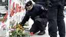 Polisi Jerman mengatur bunga yang dibawa oleh orang-orang di depan Kedutaan Besar Prancis di Berlin, Sabtu (14/11/2015). Karangan bunga tersebut untuk menghormati para korban serangan mematikan di Paris. (AFP Photo/ Tobias Schwarz)