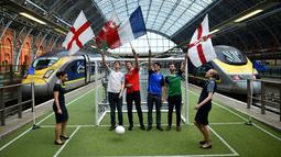 Beberapa warga mengibarkan bendera Inggris, Wales, Prancis, dan Irlandia Utara di sebuah lapangan sepak bola mini dalam Stasiun St. Pancras, London, (8/6/2016), untuk menyambut Piala Eropa 2016. (AFP/Ben Stansall)