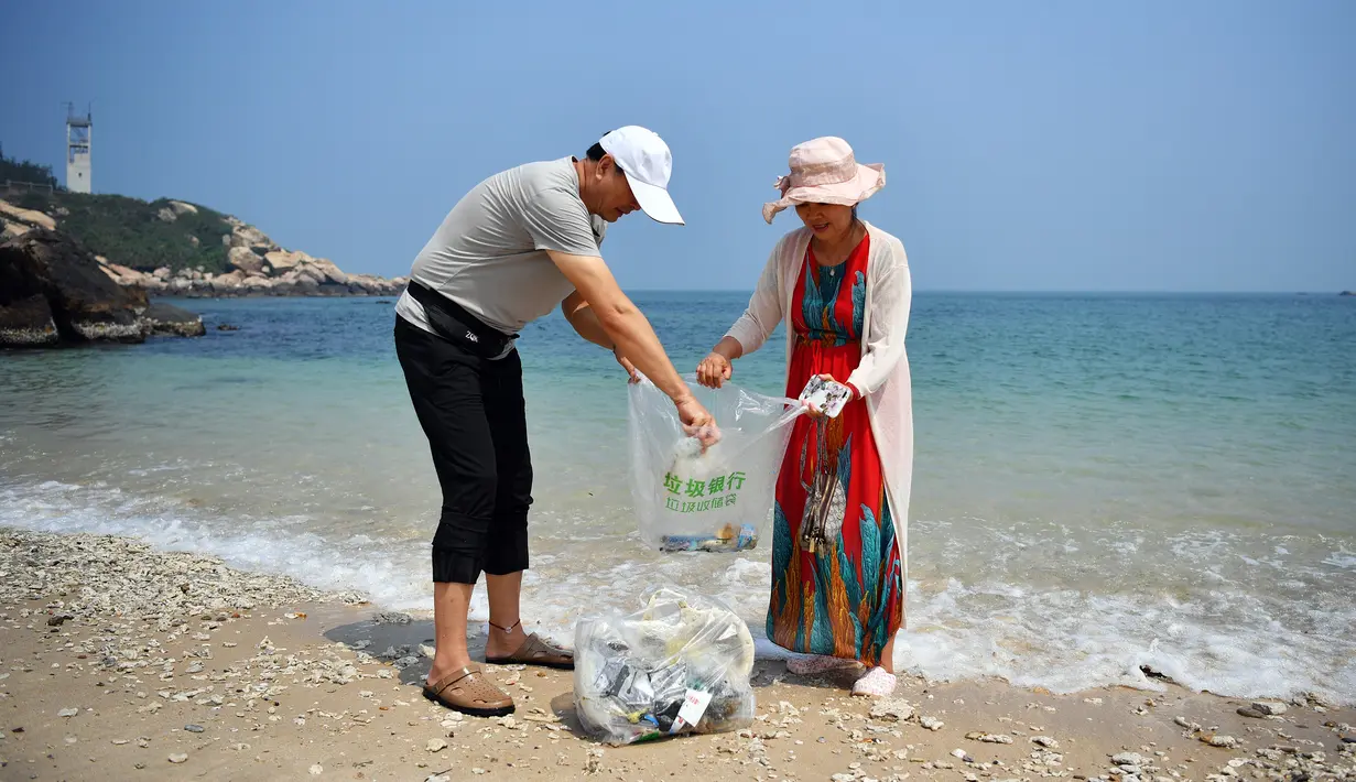 Turis mengumpulkan sampah di sepanjang Teluk Mulan, Kota Wenchang, Provinsi Hainan, China pada 28 April 2020. Fasilitas bank sampah dibuat dengan wisatawan dapat menukarkan sampah yang mereka kumpulkan di pantai dengan hadiah, seperti air kemasan, kelapa serta makanan ringan. (Xinhua/Guo Cheng)