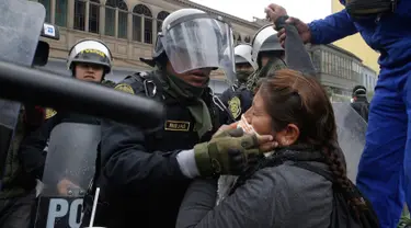 Petugas polisi membantu seorang guru yang terkena gas air mata saat unjuk rasa di Lima, Peru,  (24/8). Sejumlah  Guru sekolah umum menuntut kenaikan gaji. (AP Photo / Martin Mejia)