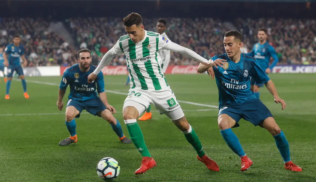 Pemain Real, Madrid Lucas Vazquez dan pemain Real Betis, Tello Herrea berebut bola pada laga pekan ke-24 La Liga Spanyol di Estadio Benito Villamarin, Minggu (18/2). Melalui pertarungan sengit 8 gol, Real Madrid menang 5-3. (AP/Miguel Morenatti)