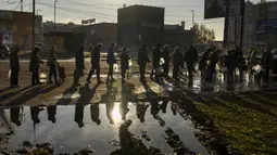 Orang-orang mengantri memegang botol plastik untuk mengisi ulang air minum dari tangki di pusat kota Mykolaiv, Ukraina, Senin (24/10/2022). Menurut pakar militer dan PBB, terputusnya pasokan air karena pasukan Rusia merusak pipa yang telah  mengaliri air minum di kota itu selama 40 tahun terakhir. (AP Photo/Emilio Morenatti)