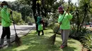 Ibu Tuti (kanan) saat bertugas menyapu taman di depan kantor Balai Kota, Jakarta, (24/3). Berkat aksi beraninya, Gubernur DKI Jakarta memberikan sebuah ponsel kamera untuk memfoto bila ada pendemo perusak taman. (Liputan6.com/Yoppy Renato)