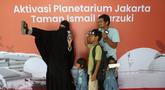Pengunjung berswafoto sebelum memasuki area Planetarium di Taman Ismail Marzuki, Jakarta, Kamis (25/12/2025). Planetarium Taman Ismail Marzuki (TIM) akhirnya dibuka kembali. Planetarium Taman Ismail Marzuki (TIM) akhirnya dibuka kembali. (Kapanlagi.com/Budy Santoso)
