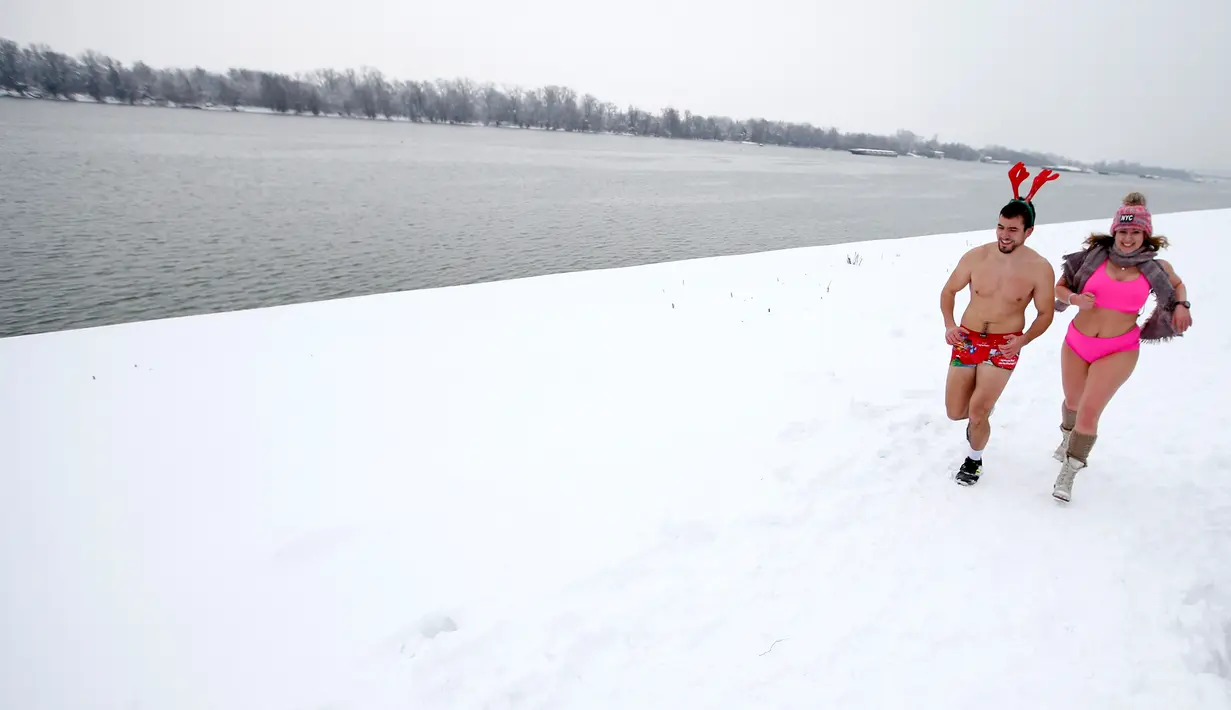Dua orang pelari ambil bagian dalam Underpants Run di tepi sungai Danube, Serbia pada 26 Januari 2019. Peserta berlari hanya dengan mengenakan pakaian dalam di tengah suhu yang mendekati 0 derajat Celcius. (AP/Darko Vojinovic)