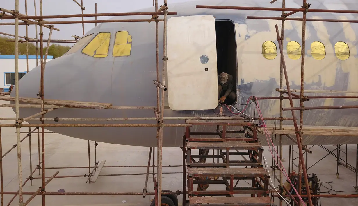 Seorang pria menyelesaikan replika pesawat Airbus A320 skala penuh di Kaiyuan, timur laut China, 25 Oktober 2018. Lima orang penggemar pesawat lainnya turut membantu seorang petani bernama Zhu Yue mempercepat penyelesaian proyek tersebut. (STR/AFP)