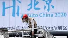 Seorang pekerja berada dekat papan bertuliskan "Hai Beijing, Auto China 2020" menjelang pameran Auto China 2020 yang akan digelar di Beijing, Kamis (24/9/2020). (AP Photo/Ng Han Guan)