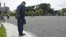 Seorang pria menundukan kepalanya di depan Istana Kekaisaran sambil mendengarkan pesan Kaisar Akihito di Tokyo, Jepang, (8/8). (REUTERS/Kim Kyung-Hoon)