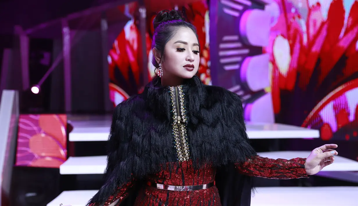 Saat tampil di Dangdut 4 Academy Asia  tahun 2018, Dewi Persik tampil glamour dengan gaun perpaudan warna merah dan hitam. Aksen blink-blink serta bulu-bulu membuat tampilan Depe semakin menawan (KapanLagi/Agus Apriyanto)