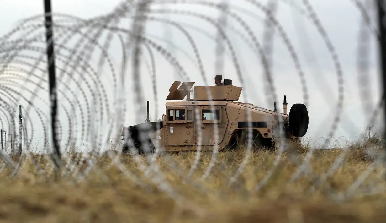 Tentara AS mengawasi sekitar dari balik barikade kawat duri dekat Jembatan Internasional AS-Meksiko di Donna, Texas,Minggu (4/11). Sebagian besar dari para imigran mengatakan berencana mengajukan permohonan suaka di AS. (AP Photo/Eric Gay)