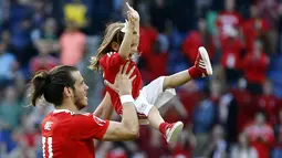 Gareth Bale merayakan kemenangan bersama putrinya usai laga melawan Irlandia Utara pada Piala Eropa 2016 di Parc des Princes, Paris, (25/6/2016). Wales Menang 1-0. (EPA/Georgi Licovski)