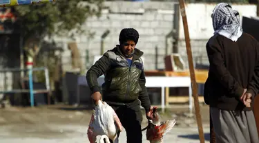 Seorang pria membawa Burung Flamingo, Irak, Selasa (24/1). Rencananya Burung Flamingo tersebut akan dijual di pasar gelap di Irak. (AFP Photo/ Haidar HAMDANI) 