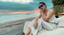 Cita Citata pancarkan pesona saat berfoto dengan latar belakang air laut kala sunset. Dengan outfit putih tulang dan tambahan aksesoris kacamata, ia seperti mutiara yang tersembunyi di laut. Angin sepoi juga meniupkan setiap helai rambutnya. (Liputan6.com/IG/@cita_citata)