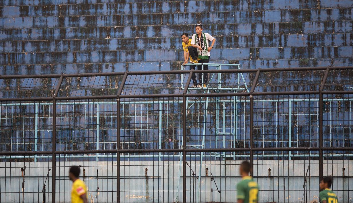 Dua orang pendukung Sriwijaya FC menyaksikan laga menghadapi Gresik United pada Piala Jenderal Sudirman di Stadion Kanjuruhan, Malang, Kamis (19/11/2015). Laga itu berlangsung sepi penonton. (Bola.com/Vitalis Yogi Trisna)