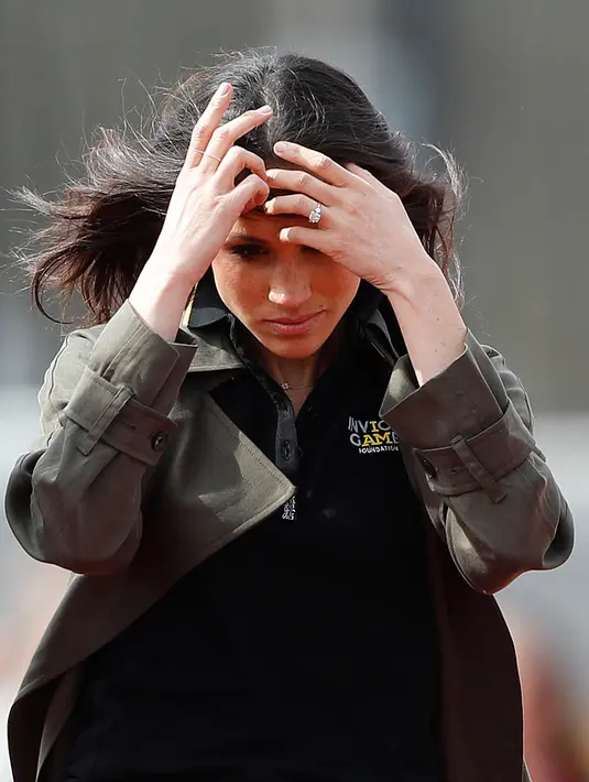 Calon istri Pangeran Harry, Meghan Markle merapihkan rambutnya saat menghadiri latihan tim Inggris untuk Invictus Games Sydney 2018 di University of Bath, (6/4). (AP Photo/Frank Augstein)