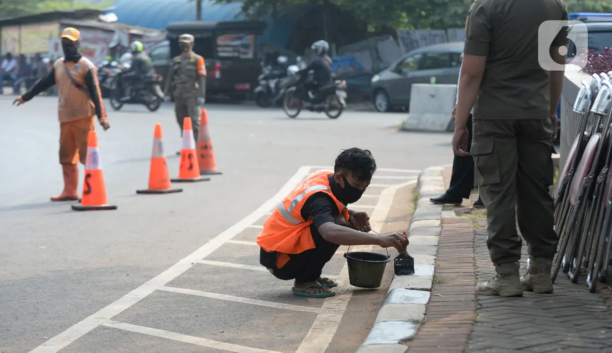 Warga terkena sanksi sosial mengcat pembatas jalan kepada warga pelanggar karena tidak menggunakan masker di Lebak Bulus, Jakarta, senin (14/09/2020). Pemerintah Provinsi DKI Jakarta memperketat kembali PSBB karena kasus Covid-19 terus mengalami peningkatan. (merdeka.com/Dwi Narwoko)