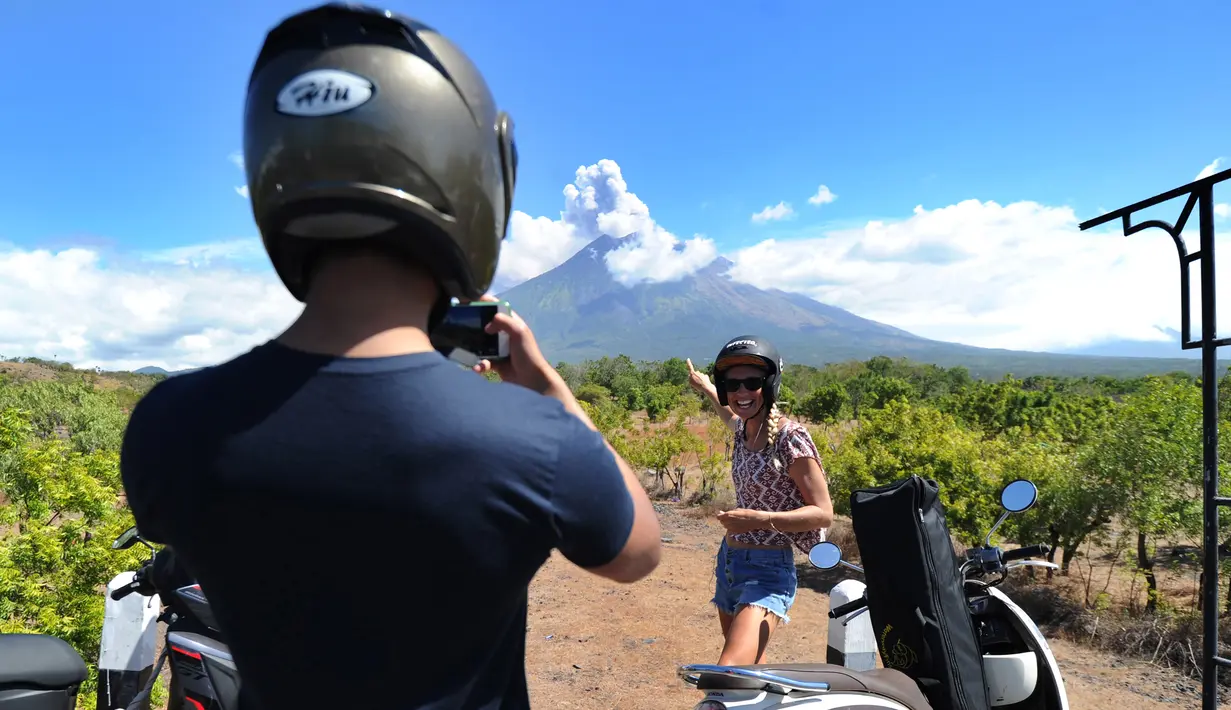 Sejumlah turis mengabadikan pemandangan erupsi Gunung Agung di Kabupaten Karangasem, Bali, Jumat (6/7). Erupsi Gunung Agung mengundang banyak perhatian warga dan wisatawan. (AFP FOTO / Sonny Tumbelaka)