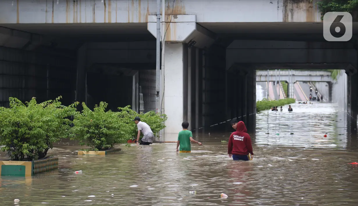 Warga melintasi banjir di terowongan Jalan Angkasa, Jakarta, Selasa (25/2/2020). Hujan yang mengguyur Jakarta sejak Senin (24/2) malam membuat sejumlah kali meluap dan menyebabkan banjir di terowongan tersebut. (Liputan6.com/Helmi Fithriansyah)