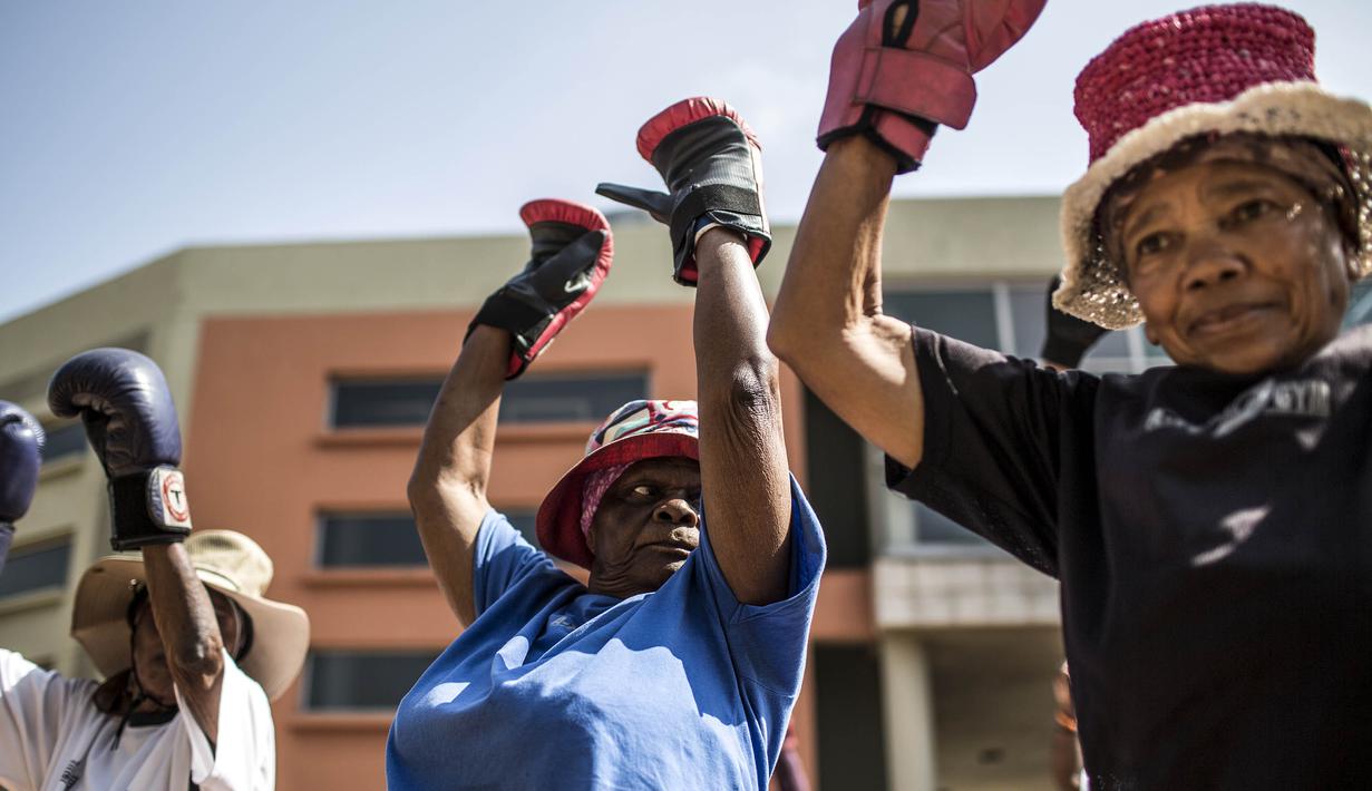 Para nenek pemanasan sebelum latihan tinju pada Boxing Gogos di Cosmo City, Johannesburg, Selasa (19/9/2017). Berkat latihan rutin yang dipimpin Claude Maphosa ini para lansia berhasil sembuh dari penyakit dan hidup lebih sehat. (AFP/Gulshan Khan) 