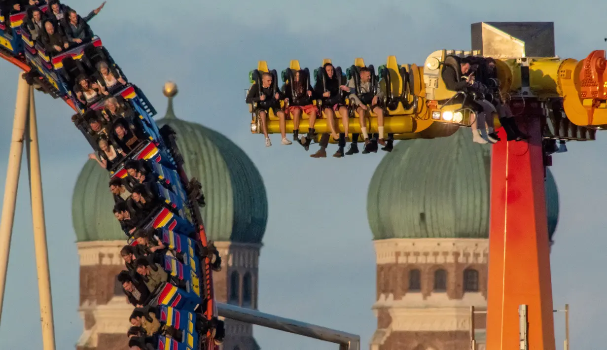 Pengunjung menaiki roller coaster di dekat Katedral Bunda Maria selama festival bir Oktoberfest di Munich, 24 September 2018. Festival ini merupakan salah satu acara paling terkenal di Jerman sejak tahun 1800an. (AFP/dpa/Peter Kneffel/ Germany OUT)