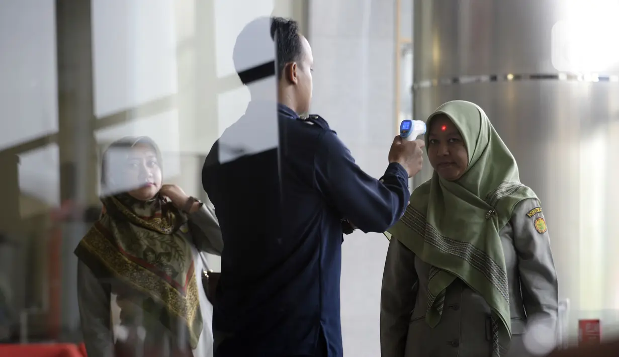 Petugas mengecek suhu tamu dan pegawai yang akan masuk ke Loby di Gedung KPK, Jakarta, Kamis, (12/3/2020). KPK menerapkan pengecekan suhu tubuh tersebut untuk mengantisipasi penyebaran virus corona atau covid-19. (merdeka.com/Dwi Narwoko)