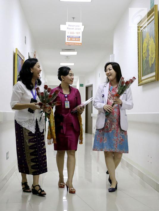 Karyawan dan dokter berjalan di lorong sambil membawa bunga dan buku kreativitas Kartini, yang akan dibagikan kepada pasien anak di RS Siloam TB Simatupang, Jakarta, Sabtu (21/4). (Liputan6.com/Fery Pradolo)
