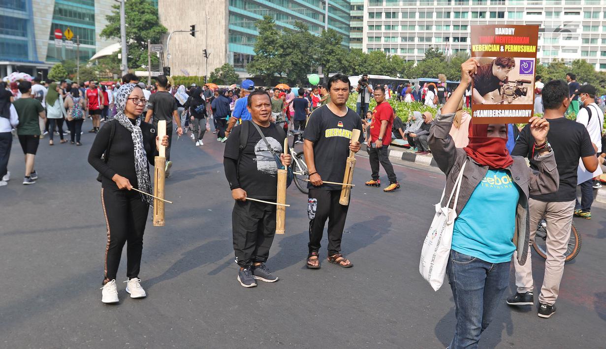 Jurnalis yang tergabung dalam Aliansi Jurnalis Independen (AJI) memainkan kentongan saat menggelar aksi menuntut pencabutan status tersangka Dandhy Dwi Laksono pada Car Free Day di Kawasan Bundaran HI, Jakarta, Minggu (29/9/2019). (Liputan6.com/Herman Zakharia)