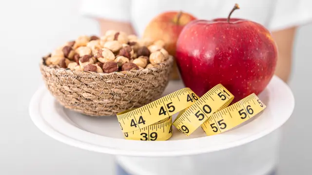 Sebuah piring dengan buah apel, kacang, dan pengukur badan (Foto Dok: Freepik/pvproductions)