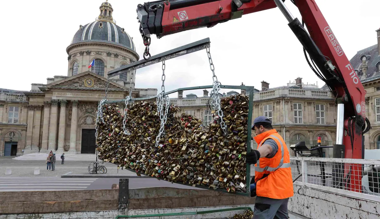 Seorang petugas menggunakan sebuah alat untuk memindahkan ribuan gembok cinta di Jembatan Pont des Arts di atas Sungai Seine, Paris, Perancis, Senin (1/6/2015). (REUTERS/Philippe Wojazer)