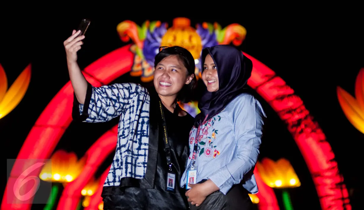 Dua orang wanita berfoto di dekat ornamen khas Imlek di kawasan Sudirman Central Business District (SCBD), Jakarta, Kamis (26/1). Pemasangan lampion ini dalam rangka menyambut perayaan Imlek 2017. (Liputan6.com/Gempur M Surya)